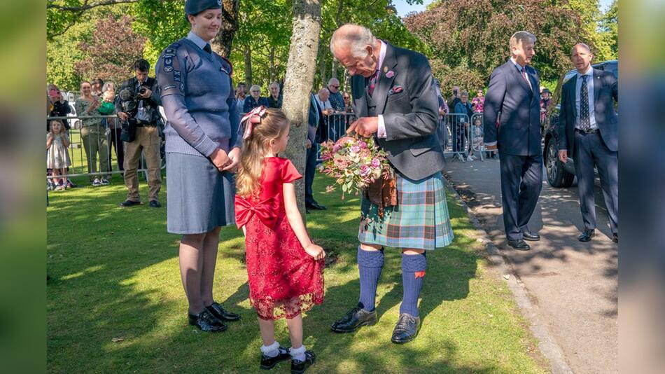 König Charles - im Schottenrock - bekommt zur Begrüssung Blumen überreicht.