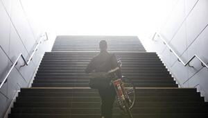 Mann trägt sein Fahrrad eine Treppe hinauf