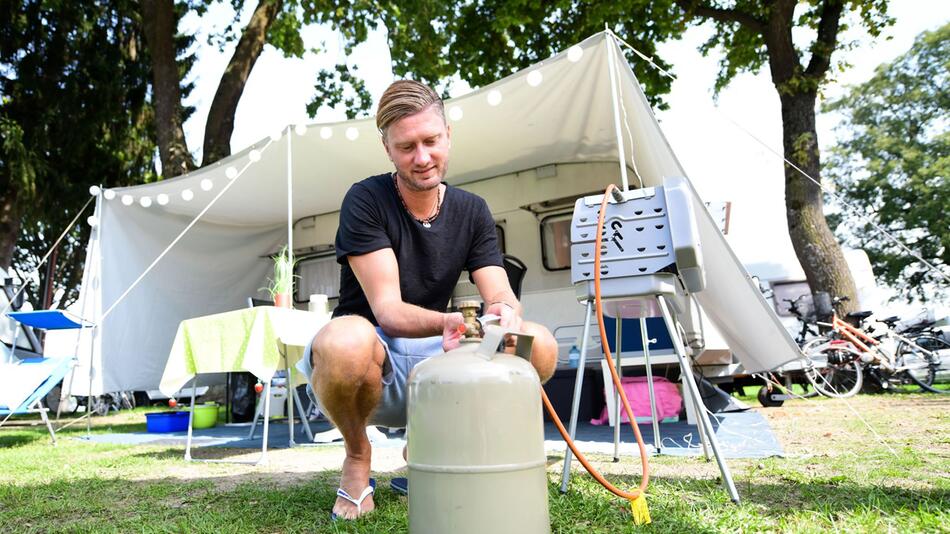 Mann schliesst eine Gasflasche an einen Grill an