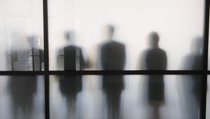 Personen stehen hinter eine Glasscheibe in einem Büro