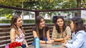 Vier Frauen sitzen am Tisch. Eine redet.