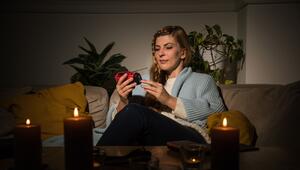 Eine Frau mit Kerzen während eines Stromausfalls auf dem Sofa