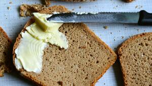 Scheibe Vollkornbrot mit Butter bestrichen, daneben ein Messer mit schwarzem Griff und ...