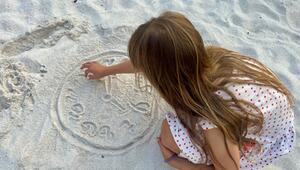 Kind malt eine Uhr in den Sand