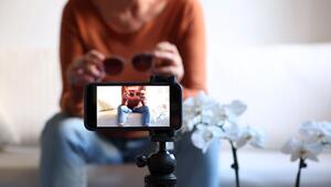 Frau mit Sonnenbrille in der Hand filmt sich mit dem Smartphone
