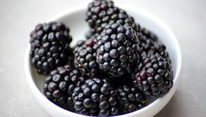 Schwarze Brombeeren in einer weissen Schale vor hellem Hintergrund.