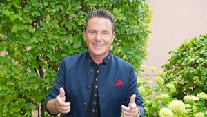 Stefan Mross lächelt und streckt Daumen nach oben und richtet Zeigefinger nach vorne.