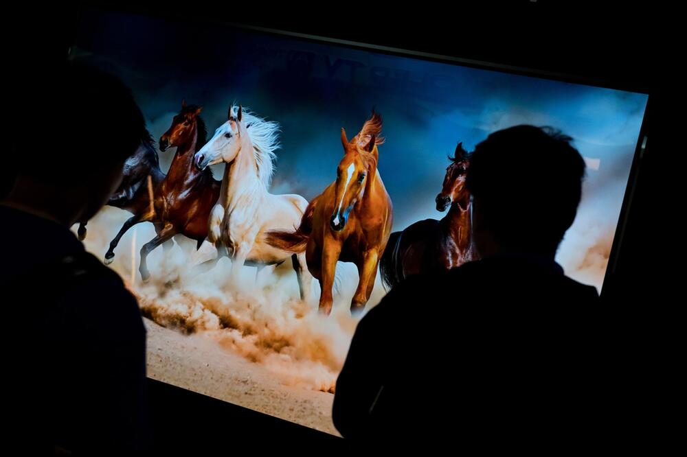 Personen stehen vor einem 88-Zoll OLED-TV mit 8K-Auflösung