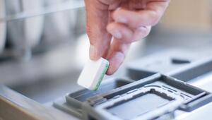 Mann legt einen Geschirrspültab in eine Spülmaschine