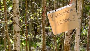Handgeschriebener Zettel, der vor Waldbrandgefahr warnt