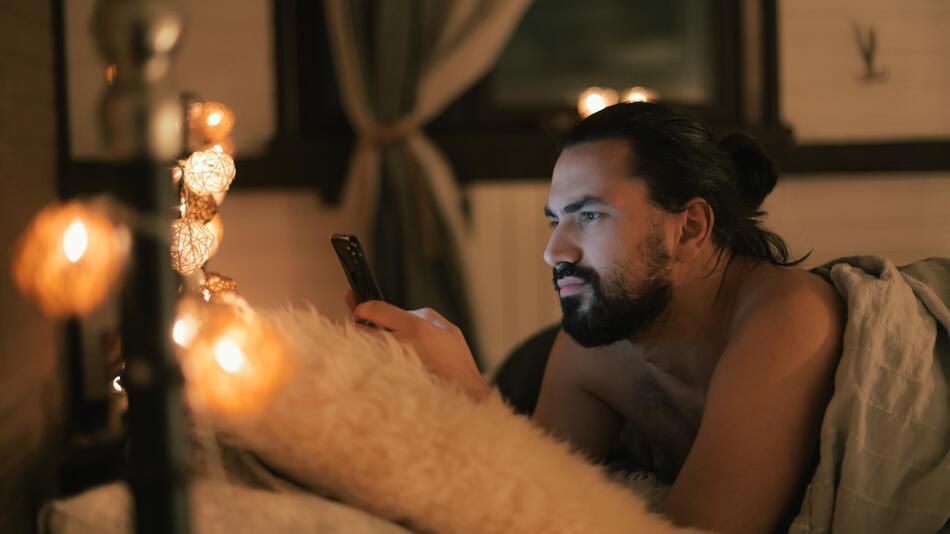 Mann mit Telefon im Bett