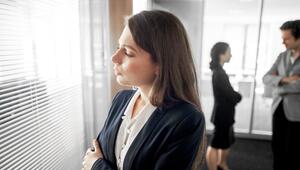 Frau steht abseits ihrer Kollegen in einem Büro