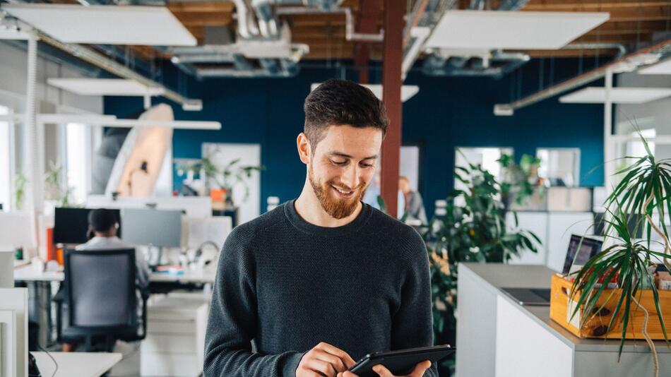 Mann mit Tablet in einem Grossraumbüro