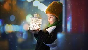 Kleine Junge hält eine Kerzenlaterne mit leuchtenden Augen in den Händen