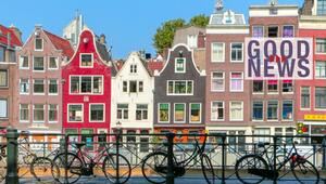 Typische Amsterdamer Giebelhäuser in verschiedenen Farben, davor eine Brücke mit mehreren ...