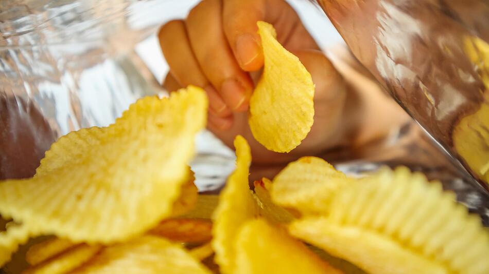 Hand greift in Chipstüte