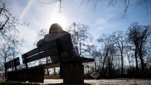 Eine Frau sitzt neben kahlen Bäumen in der Sonne