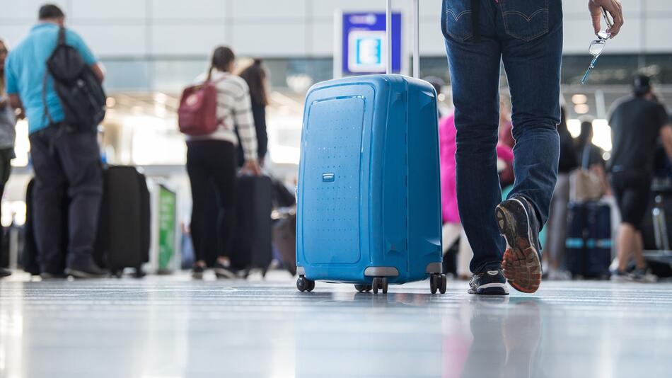 Ein Passagier geht mit einem Koffer Flughafen