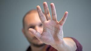 Ein Mann hebt schützend die Hand vor sein Gesicht