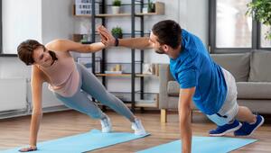 Eine Frau und ein Mann stützen sich je mit einem Arm auf einer Yogamatte ab.