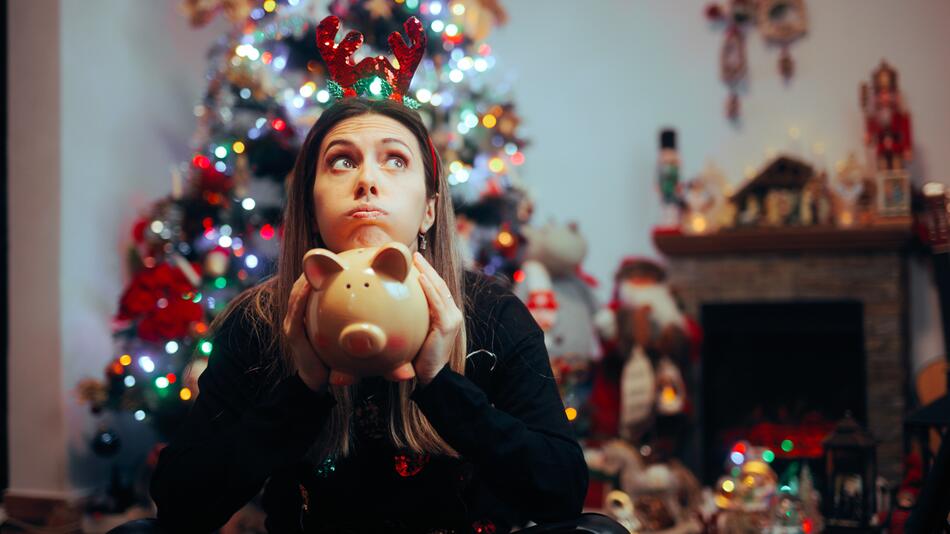 Frau hält an Weihnachten verzweifelt ein Sparschwein in der Hand