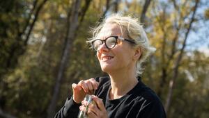 Eine Frau trinkt in einem Wald aus einem Campingbecher