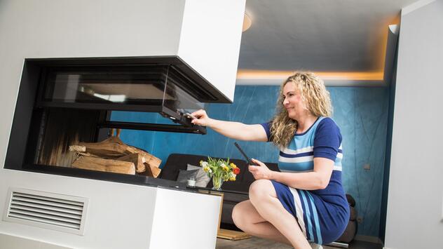 Eine Frau öffnet einen Kaminofen