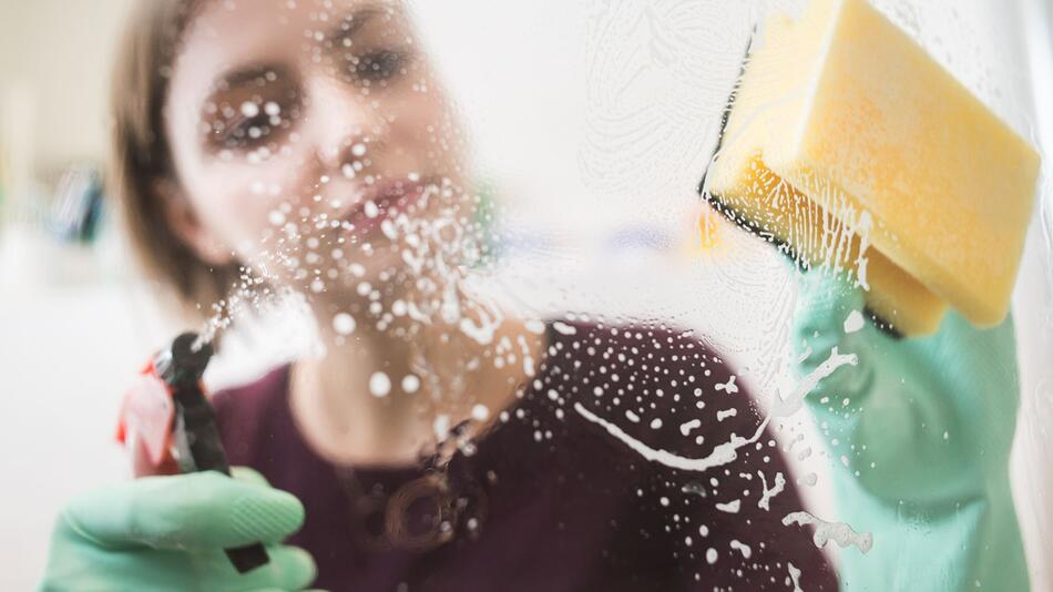 Frau putzt die Dusche im Badezimmer