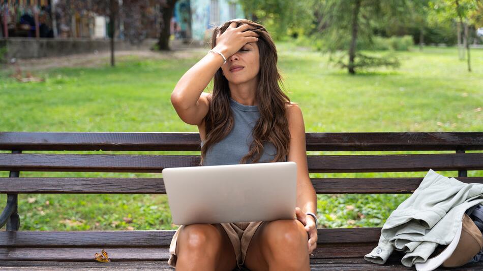 Eine Frau mit einem Laptop auf dem Schoss.