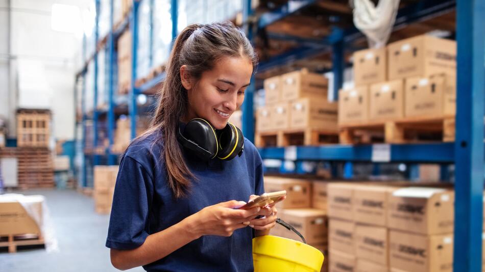 Frau arbeitet im Lager und schaut auf Handy