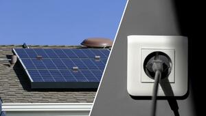 Solarmodule auf einem Hausdach bei klarem Himmel und eine weisse Steckdose mit eingestecktem ...