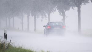 Ein Auto fährt bei Starkregen über eine Landstrasse