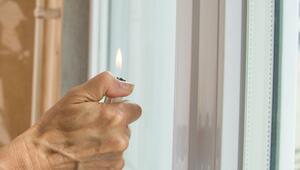 Eine Frau hält ein Feuerzeug an ein Fenster