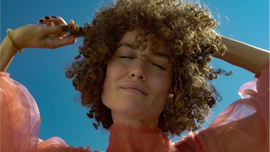 Frau spielt mit ihren Locken.