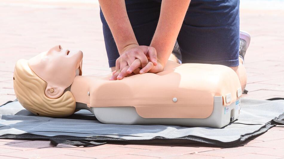 Eine Person übt eine Herzdruckmassage an einer Erste-Hilfe-Puppe