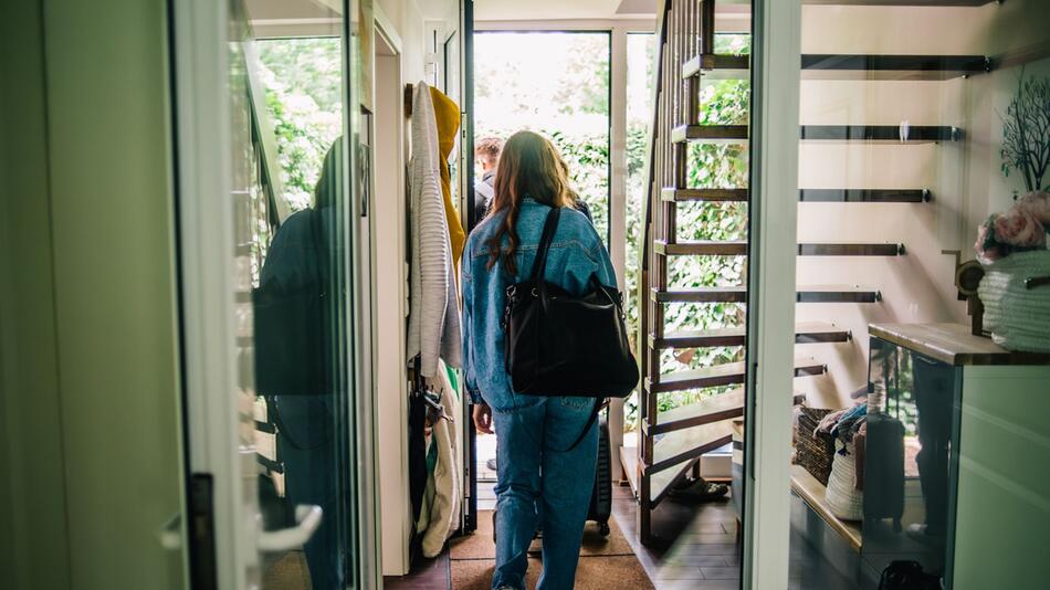 Eine junge Frau verlässt ein Haus