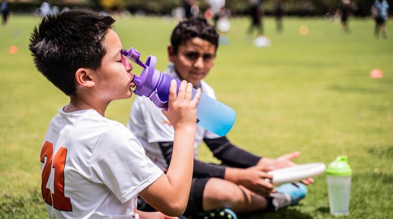 Junge trinkt Wasser am Sportplatz