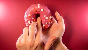 Ein Finger wird in einen Donut gesteckt