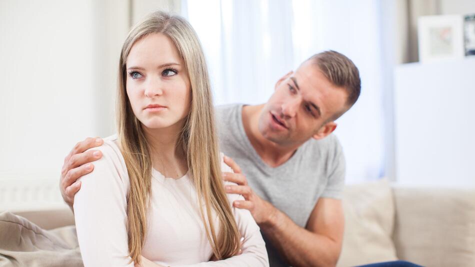 Frau sitzt enttäuscht neben ihrem Partner