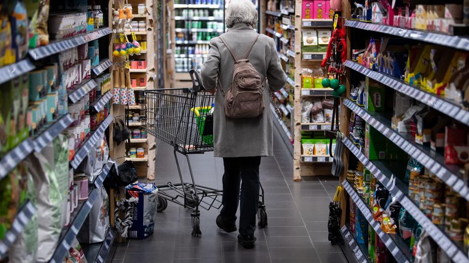 Eine Frau geht mit Einkaufswagen durch einen Supermarkt