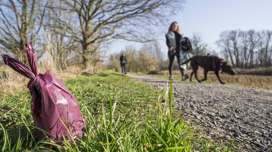 Frau mit Hund im Vordergrund ein Hundekotbeutel