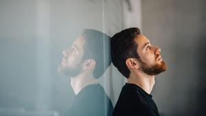 Ein junger Mann lehnt nachdenklich an einer Glaswand