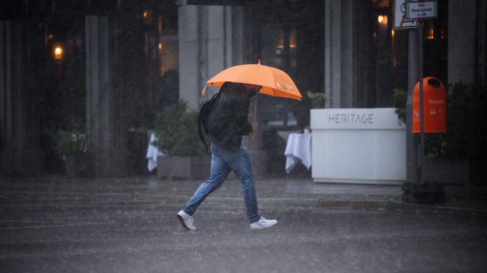 Ein Mann mit Regenschirm im Starkregen