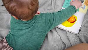 Ein sieben Monate altes Baby spielt auf einer Decke