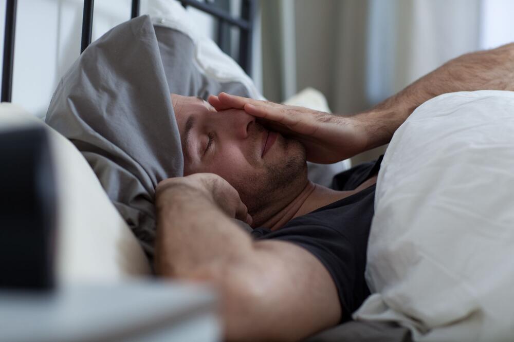 Ein Mann liegt mit Schlafstörungen im Bett