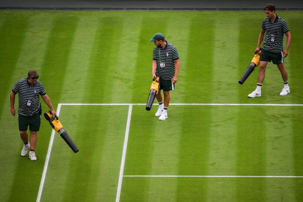 Helfer rücken mit mächtigen Föhns an und trocknen den Center Court in Wimbledon am 3. Juli 2023