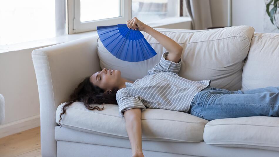 Frau liegt mit Fächer auf dem Sofa