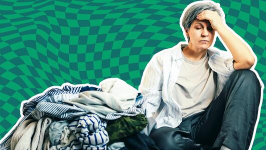 Frau, die genervt neben Wäschebergen sitzt. 