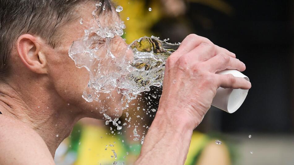 Ein Mann schüttet sich Wasser ins Gesicht