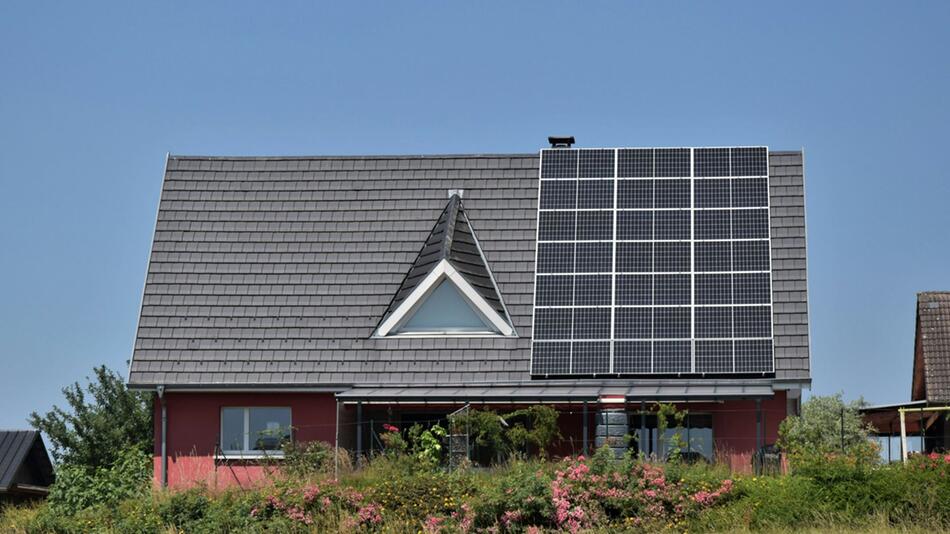 Einfamilienhaus, auf dem Solarpaneele installiert sind. Der Himmel ist klar und blau.